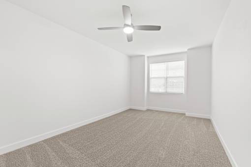 A room with a ceiling fan and carpeted floor.