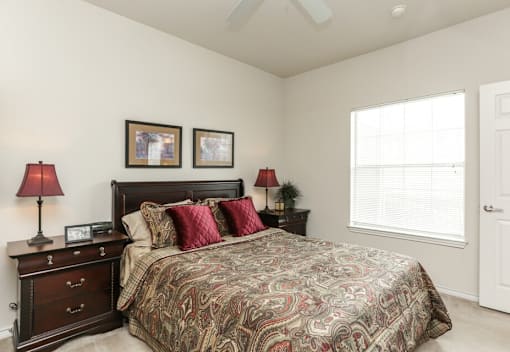 A bedroom with a large bed and two lamps on either side of the bed.