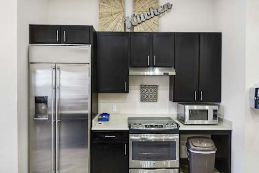 a kitchen with black cabinets and stainless steel appliances and a refrigerator