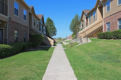A concrete walkway leads between two rows of apartment buildings.