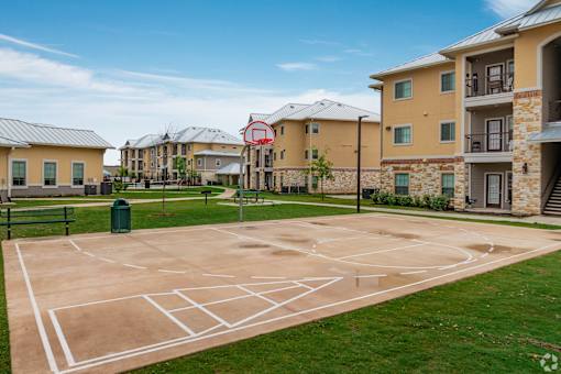 A basketball court in front of apartment buildings.