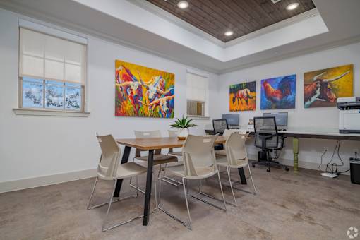 A room with a table, chairs and artwork on the wall.