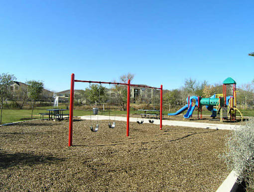A playground with a red swing set and a blue slide.