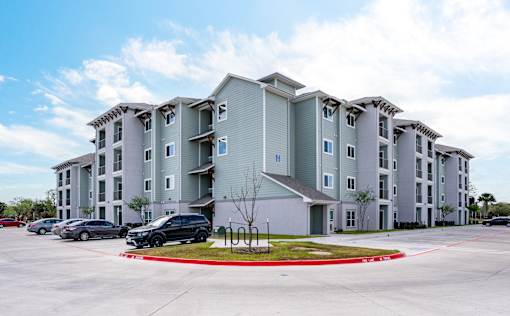 A large apartment complex with a parking lot in front.