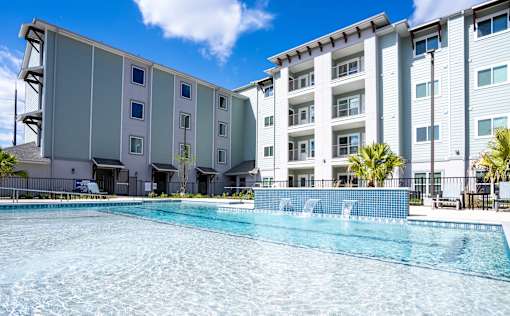 A large swimming pool in front of a multi-story residential building.