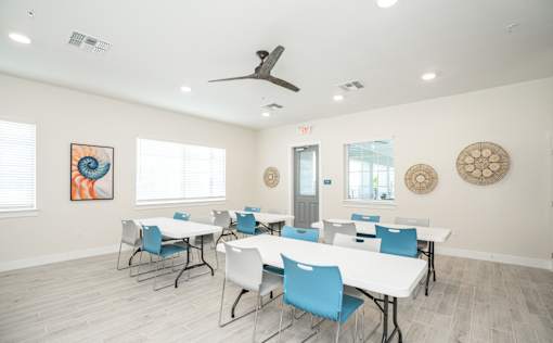 A room with a white table and blue chairs.