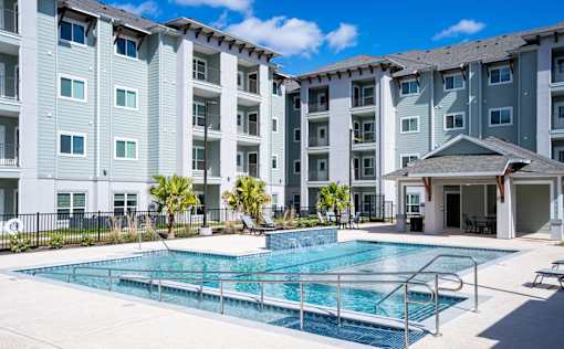 A swimming pool in front of a multi-story apartment building.