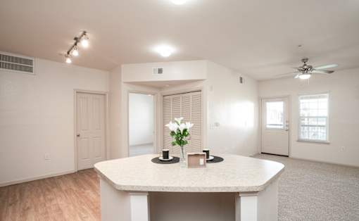 A spacious room with a table, chairs, and a vase of flowers.