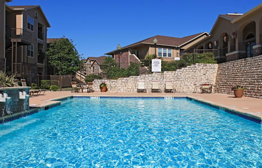 A swimming pool in a residential area with houses and trees in the background.