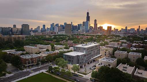 A cityscape with a sunset in the background and a mix of residential and commercial buildings.