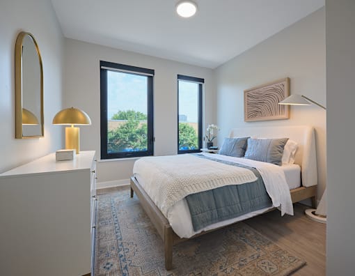 A bedroom with a large bed and a view of trees outside the window.