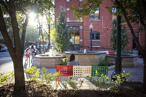 A woman is sitting on a bench in a park.
