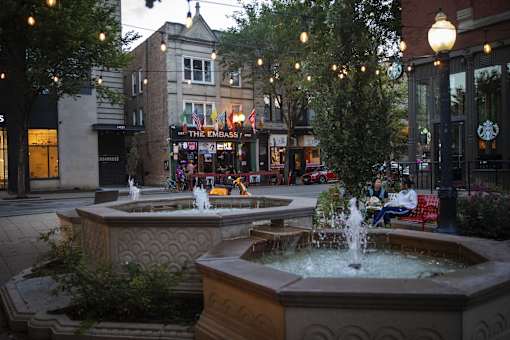 A fountain in the middle of a plaza with a sign that says "The Embassy".