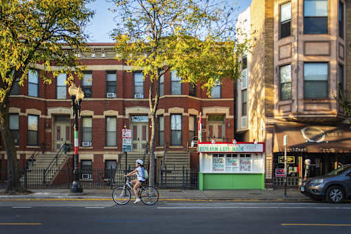 A person riding a bike in front of a red brick building.