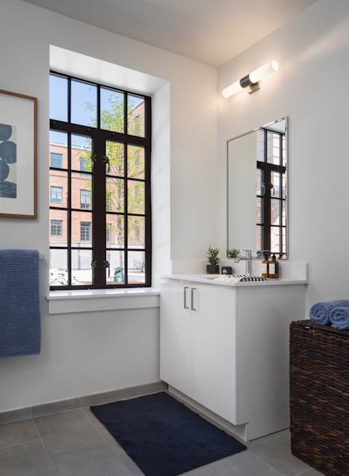 a white bathroom with a window and a sink and mirror