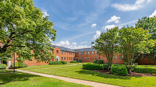 A large red brick building with a green lawn in front.
