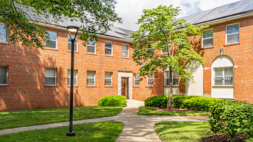 A red brick building with a tree in front.
