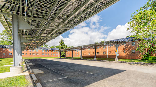A long building with a metal roof and a parking lot in front.