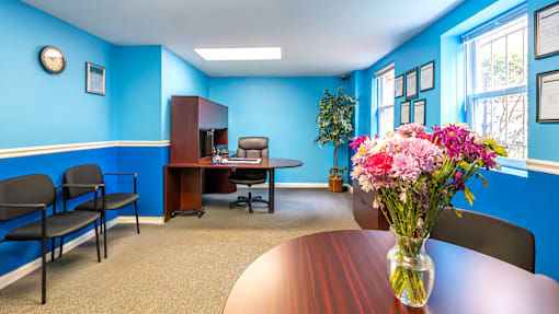 A conference room with a table, chairs, and a vase of flowers.