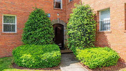 A red brick building with green bushes in front.
