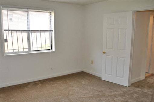 A room with a white door and a window with blinds.