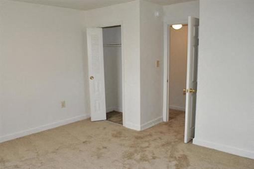 A room with a carpeted floor and two doors.