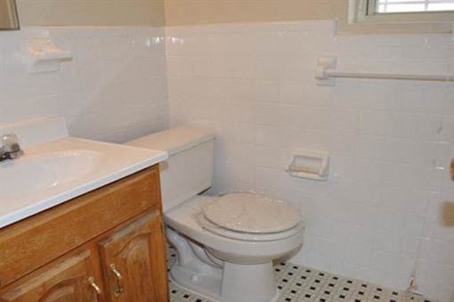 A white toilet in a bathroom with a sink and wooden cabinets.