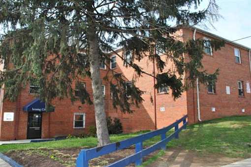 A red brick building with a blue fence and a tree in front.