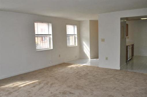 A room with two windows and a door is empty and waiting to be furnished.