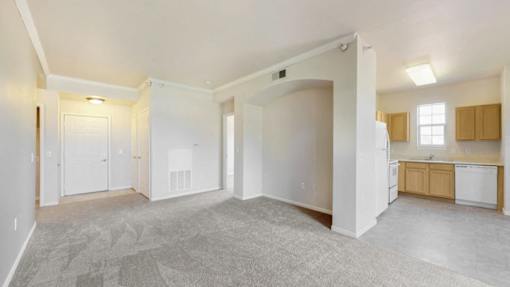 the living room and kitchen of an empty home with white walls