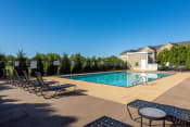 a pool with chairs and a table in front of a building