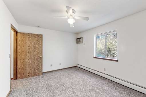 an empty bedroom with a ceiling fan and a window