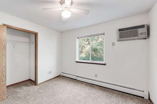 an empty room with white walls and a window and a ceiling fan