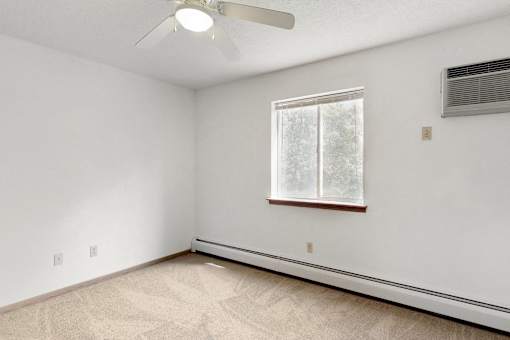 an empty room with a window and a ceiling fan