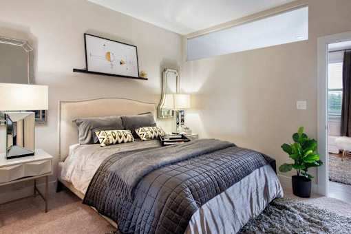A bedroom with a large bed and a potted plant at The Olivia Apartments, Carmel 46032