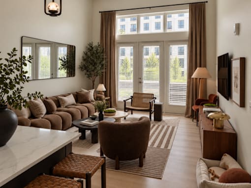 A living room with a large window and a view of a building outside.