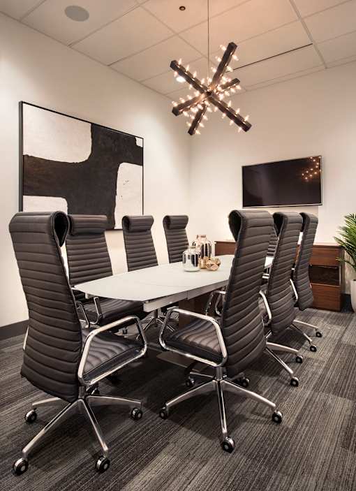 A conference room with a large table surrounded by chairs and a chandelier hanging from the ceiling at The Olivia Apartments, Carmel, IN, 46032