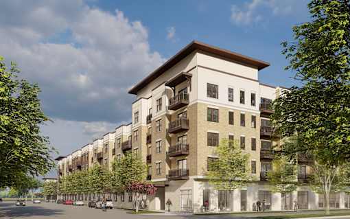 A modern apartment building with a mix of beige and white exterior walls, surrounded by trees and a clear blue sky.