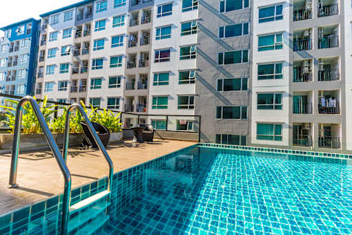 A swimming pool in front of a multi-story residential building.