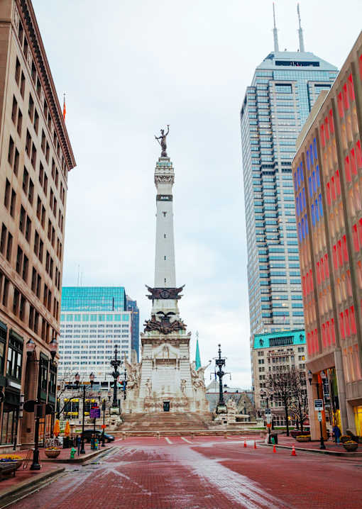 A city street with a tall white monument in the middle.