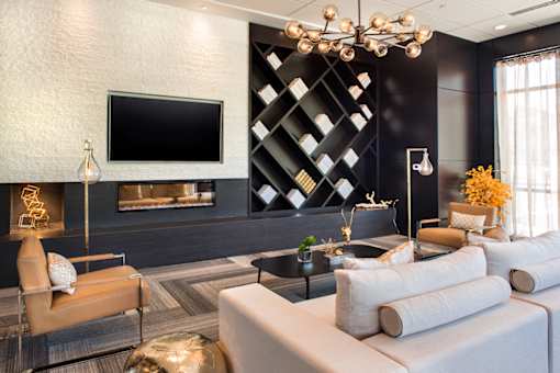A modern living room with a large television and a fireplace at The Olivia Apartments, Carmel