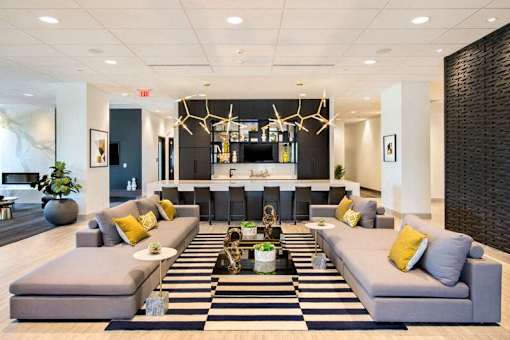 A modern living room with a black and white striped rug and grey couches at The Olivia Apartments, Carmel, IN, 46032