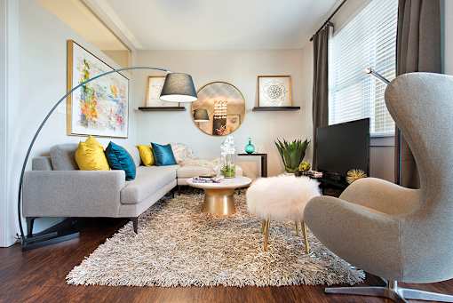 A living room with a grey couch, a white chair, and a coffee table. at The Olivia Apartments, Carmel, IN