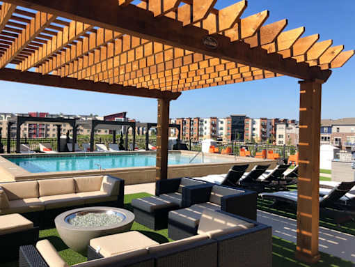 A wooden pergola over a patio with a pool in the background at The Olivia Apartments, Carmel 46032