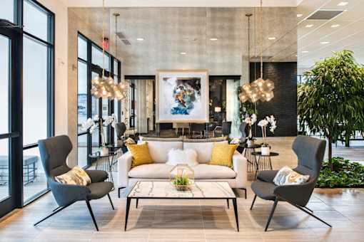 A modern living room with a large painting on the wall and a comfortable seating area at The Olivia Apartments, Indiana, 46032