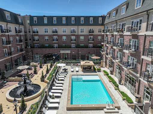 A large pool surrounded by a fence and a building in the background.