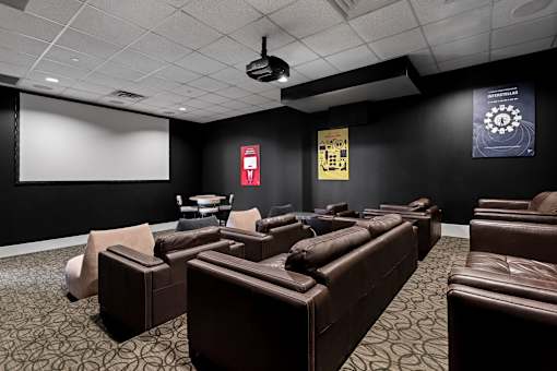A dark room with a screen and chairs.