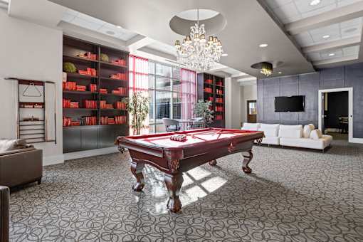 A pool table is in the middle of a room with a grey carpet.