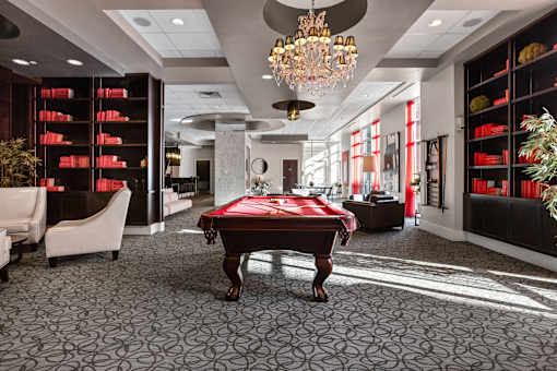 A room with a pool table and a chandelier.