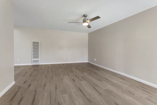 A room with a ceiling fan and light fixture, and a wall-mounted air vent.